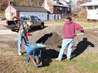 Boyscouts from Troop 21 shovel RAP (recycled asphalt) into a wheelbarrow to be used as the primary path material at Benson Park in Hudson, NH.